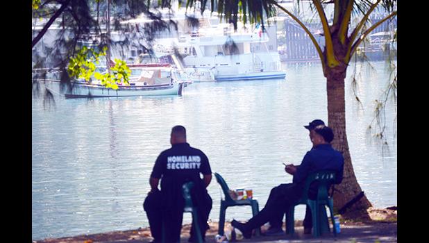 Homeland security personnel siting on shore in sight of yacht