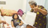 First Lady, Cynthia Moliga presenting a gift to a young girl at the Pediatric Ward at LBJ hospital yesterday during the Governor’s annual visit for the holiday season. [photo by AF]